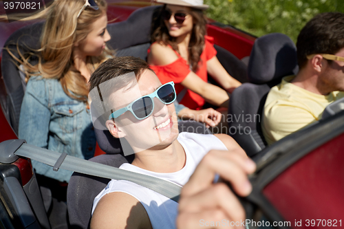 Image of happy friends driving in cabriolet car