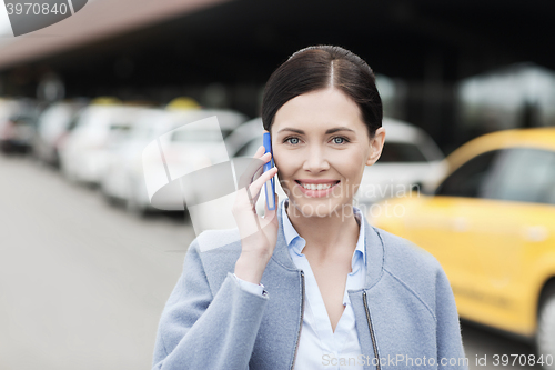 Image of smiling woman with smartphone over taxi in city