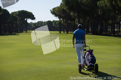 Image of golf player walking with wheel bag