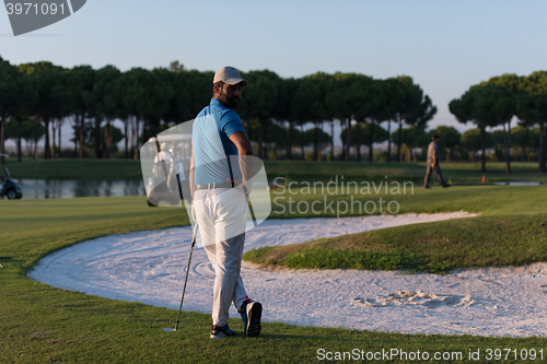 Image of golfer from back at course looking to hole in distance