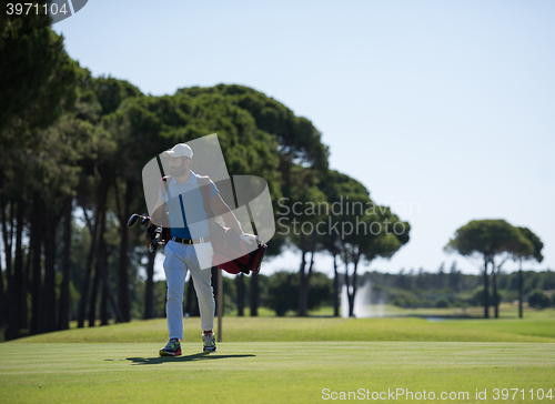 Image of golf player walking and carrying bag