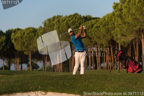 Image of golfer hitting a sand bunker shot on sunset