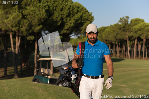 Image of golfer  walking and carrying golf  bag