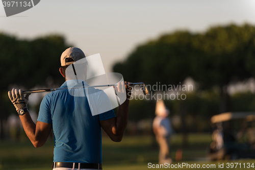 Image of golfer from back at course looking to hole in distance