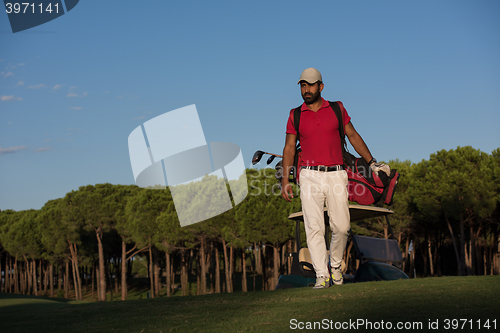 Image of golfer  walking and carrying golf  bag