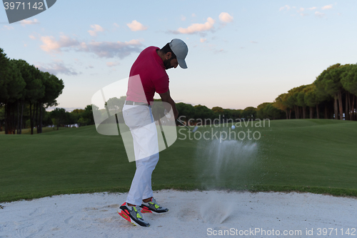 Image of golfer hitting a sand bunker shot on sunset