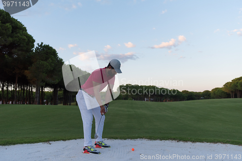 Image of golfer hitting a sand bunker shot on sunset