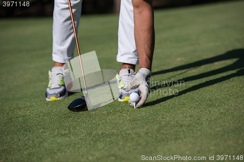 Image of golf player placing ball on tee