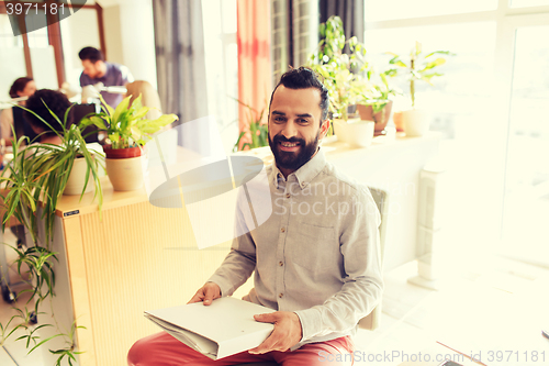 Image of happy creative male office worker with folfer