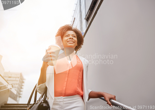 Image of happy african businesswoman with coffee in city