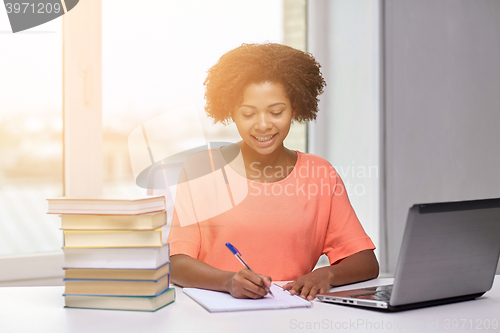 Image of happy african american woman with laptop at home