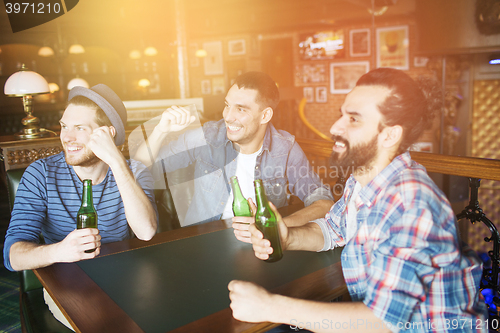 Image of happy male friends drinking beer at bar or pub