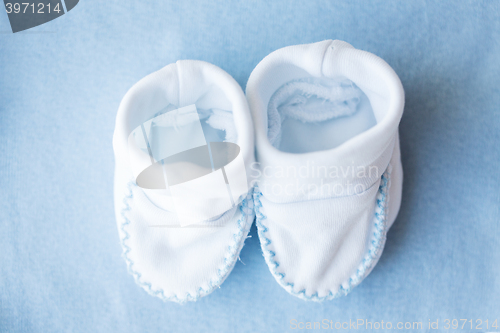 Image of close up of baby bootees for newborn boy on blue