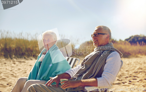 Image of happy senior couple in chairs on summer beach