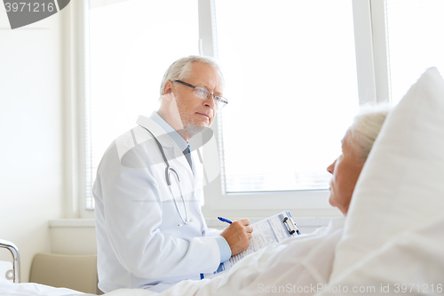 Image of senior woman and doctor with clipboard at hospital