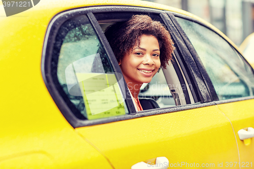 Image of happy african american woman driving in taxi