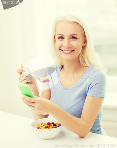 Image of smiling woman with smartphone eating  breakfast 