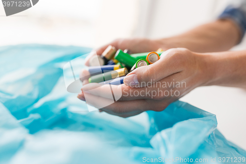 Image of close up of hands putting batteries to rubbish bag