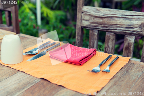 Image of close up of cutlery with glass and napkin on table