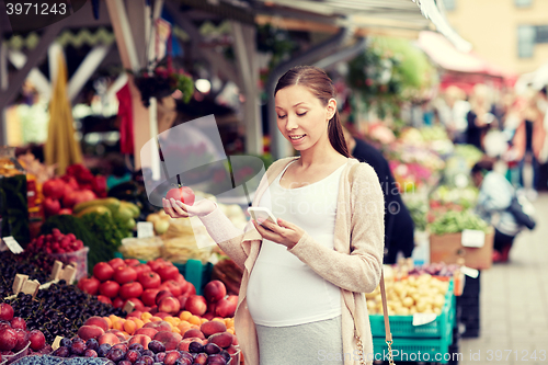 Image of pregnant woman with smartphone at street market