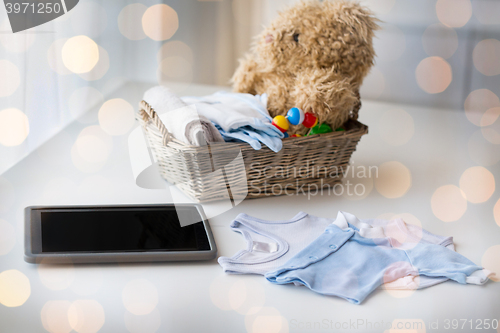 Image of close up of baby clothes, toys and tablet pc