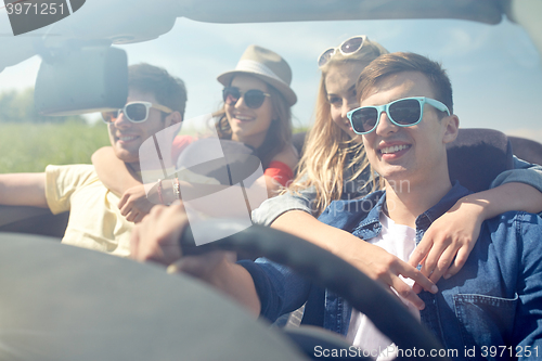 Image of happy friends driving in cabriolet car outdoors