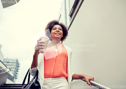 Image of happy african businesswoman with coffee in city