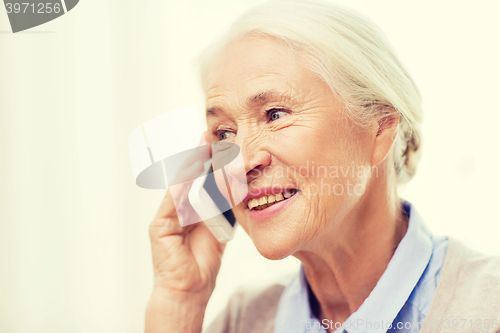 Image of senior woman with smartphone calling at home