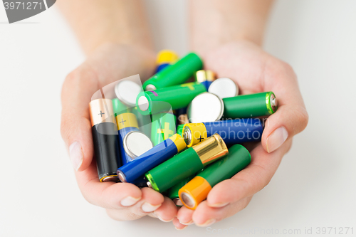 Image of close up of hands holding alkaline batteries heap