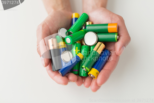 Image of close up of hands holding alkaline batteries heap