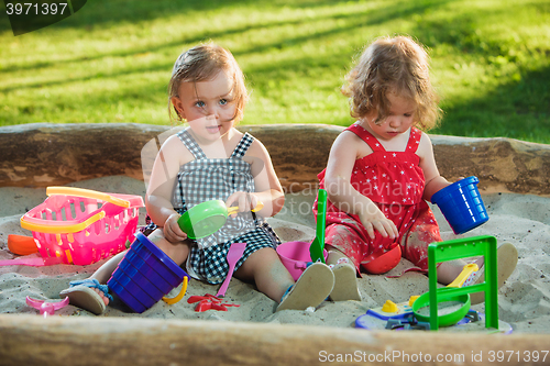 Image of The two little baby girls playing toys in sand