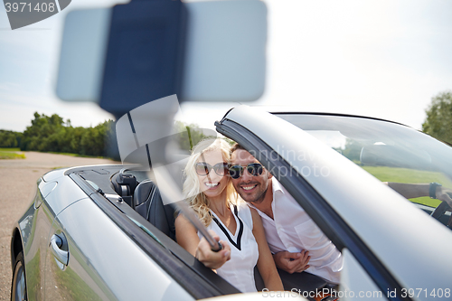 Image of happy couple in car taking selfie with smartphone