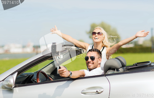 Image of happy couple in car taking selfie with smartphone