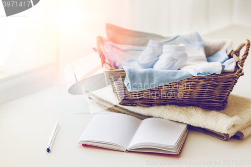 Image of close up of baby clothes for newborn and notebook