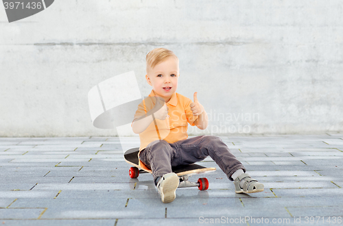 Image of happy little boy on skateboard showing thumbs up