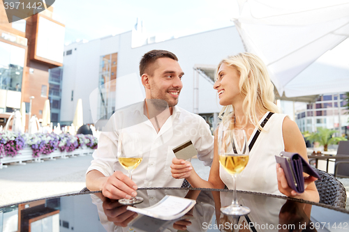 Image of happy couple with wallet paying bill at restaurant