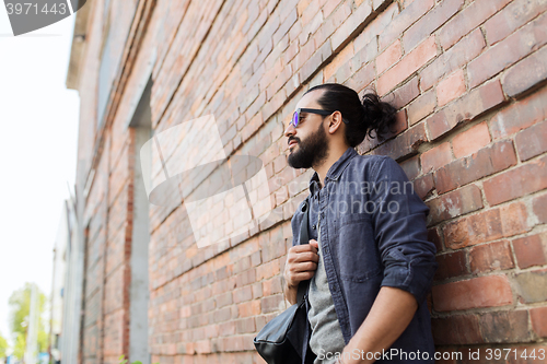 Image of man with backpack standing at city street wall