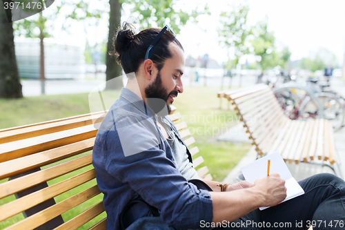 Image of man with notebook or diary writing on city street