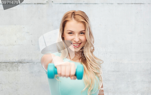 Image of smiling beautiful young sporty woman with dumbbell