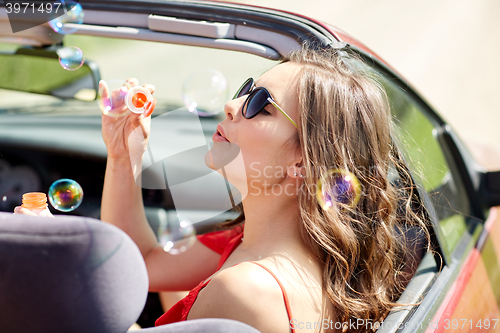 Image of woman blowing bubbles in convertible car