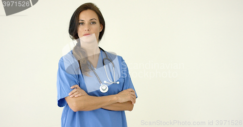 Image of Woman in scrubs crosses arms and smiles at camera