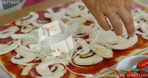 Image of Woman placing onion on a homemade pizza