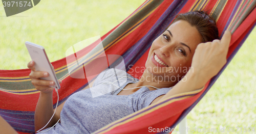 Image of Happy young woman listening to music in a hammock