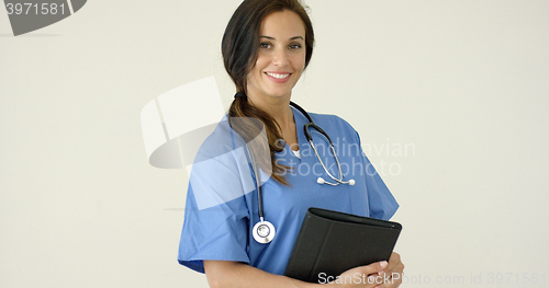 Image of Woman in scrubs holds black portfolio and smiles