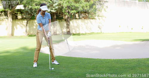 Image of Woman golfer about to play a stroke on the green