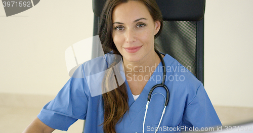 Image of Young female physician places one hand on her face