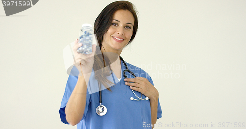 Image of Young brown haired doctor in scrubs holds bottle