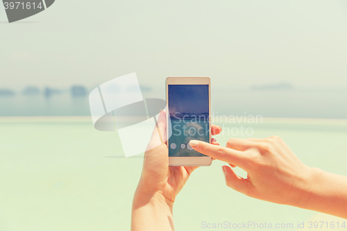 Image of close up of female hand with smartphone on beach