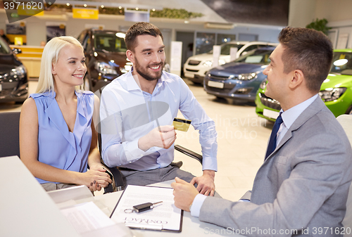 Image of happy couple with car dealer in auto show or salon