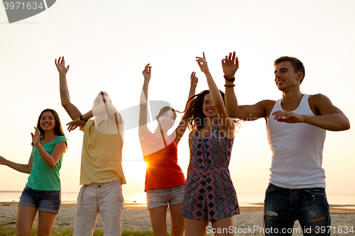 Image of smiling friends dancing on summer beach